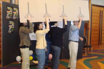 team holding  cardboard sign out of the box creative team building activity
