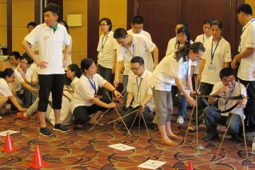 employees collaborate to complete breakthrough team building activity