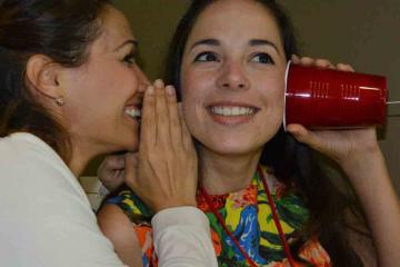 two women communicating via a cup phone in team building game quickfire