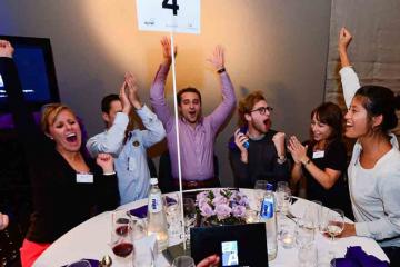 people sat around a conference table during dinner cheering at a team building activity
