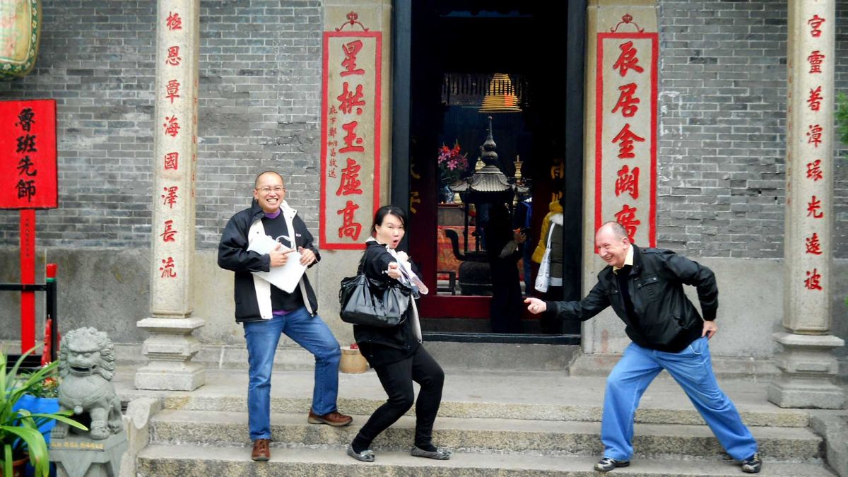 team striking a funny pose outside a building during travel show outdoor team building activity
