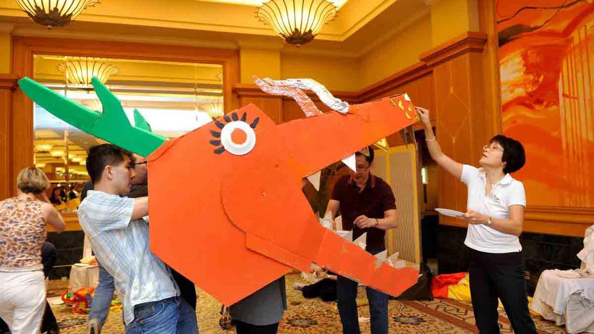 three people cooperating to create a dragons head in Catalyst teambuilding activity Dragons Squad